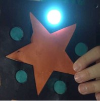 child holding paper with star and circles, with light shining through one circle